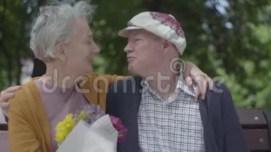 成年妇女抱着一束美丽的花，而她年迈的丈夫拥抱着她。<strong>温情</strong>的成年夫妇